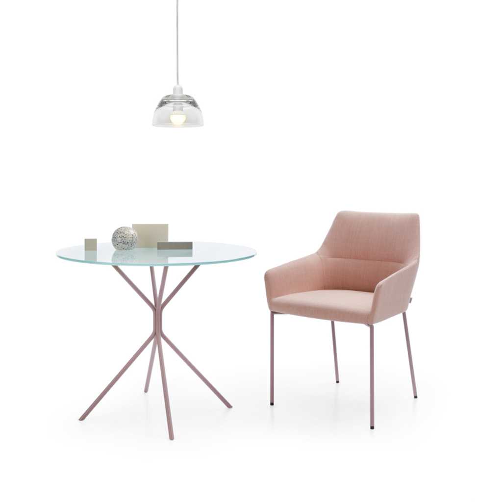 Coralfarbener Polsterstuhl mit Armlehnen, neben einem Beistelltisch mit Glasplatte. Über dem Tisch hängt eine kleine Lampe.
