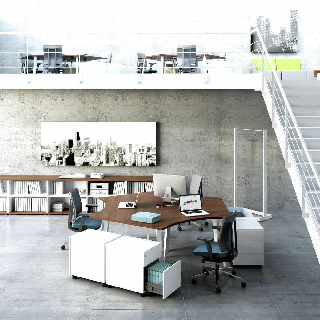 Team Schreibtisch Gruppenschreibtisch in einem großen Büroraum für ein dreier Team. Weiße Standcontainer neben den Schreibtischen. Auf den Schreibtischplatten mit Holzdekor stehn Arbeitsunterlagen und Geräte. In Hintergrund ein Aktensideboard und darüber ein Bild mit der Silhoutte einer Stadt. Es hängt an eienr Betonwand.