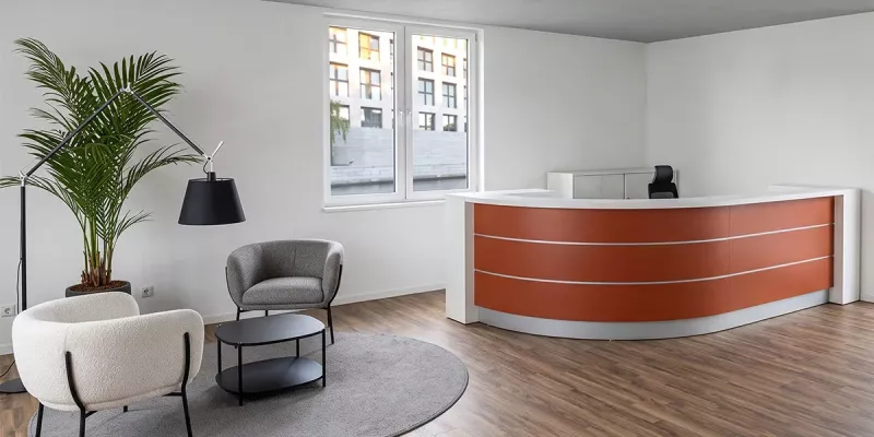 Empfangsbereich mit roter Theke und kleinem Wartebereich
