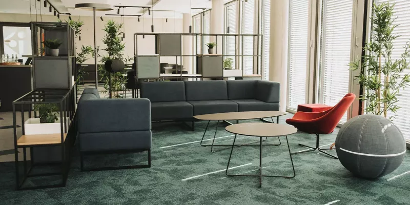 Im Pausenraum integrierter Loungebereich mit 3-Sitzer-Sofas, Sesseln und Sitzbällen