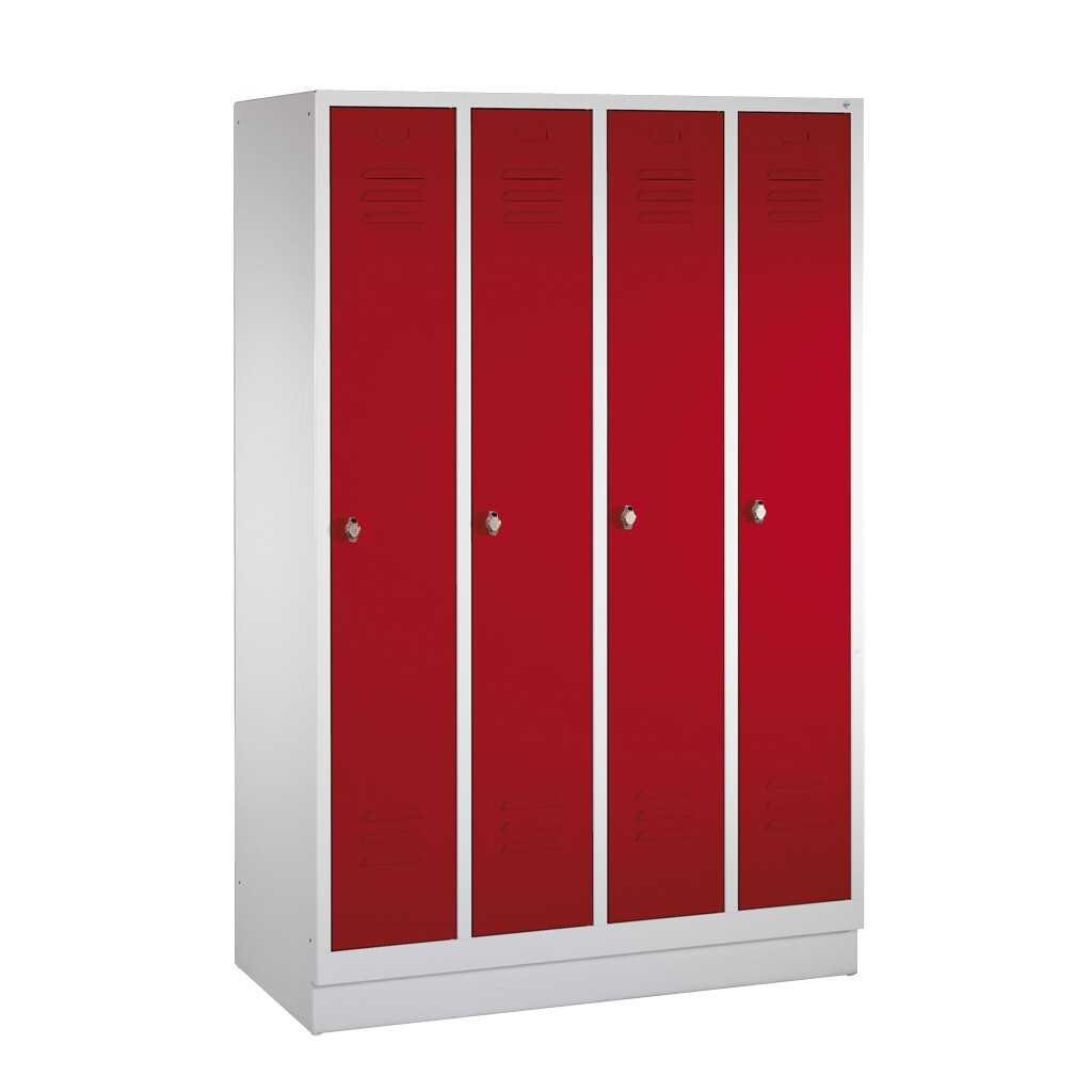Abschließbare Kleiderspinde Schrank mit vier Kleiderspinden. Die Türen sind rot, der Korpus weiß. Oben und unten in den Spindtüren befinden sich je drei waagerechte Lüftungsschlitze.