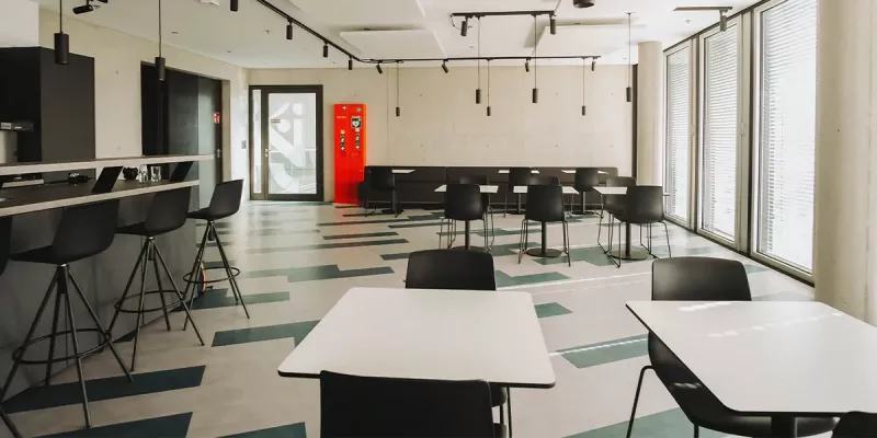 Cafeteria mit bodentiefen Fenstern, Theke und Sitzgruppen