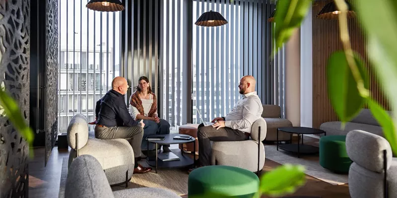 Loungebereich mit Sesseln und Sofas sowie Deckenleuchten mit Akustikschirm