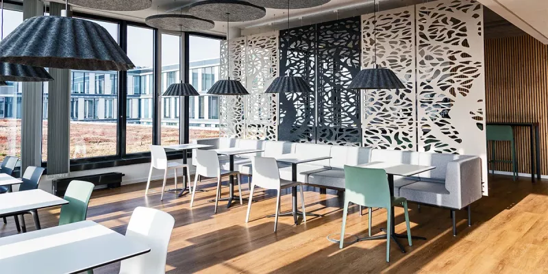 Cafeteria mit großen Fesntern und hellen, gemütlichen Möbeln