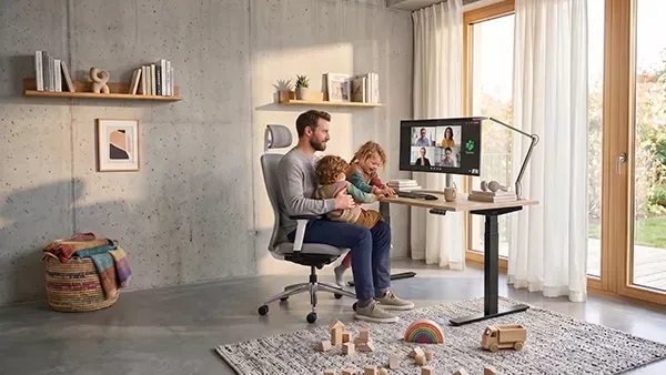 Mann sitzt mit seinen zwei Kindern auf dem MasterChair Premium in Homeoffice-Umgebung