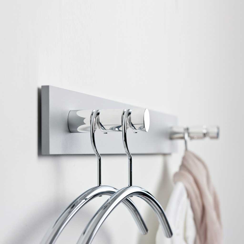Minimalistische Wandgarderobe Garderobe zur Befestigung an der Wand. Schlichte Chromelemente und Kleiderbügel. An der Garderobe hängt ein Kleidungsstück.