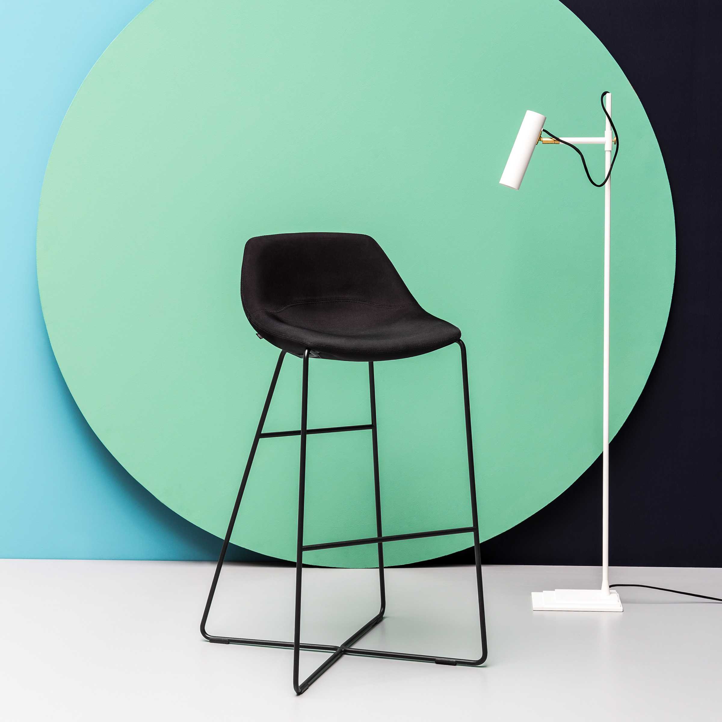 Design Barhocker moderner Barhocker im minimalistischen Design. Ganz in Schwarz vor einem kreisrunden mintfarbendem Dekoobjekt. Rechts eine silberne Stehlampe.