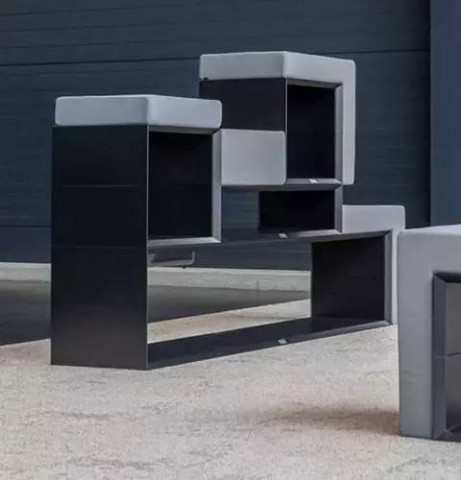 Schwarzer Masterboxen als flacher Raumteiler gestapelt und mit grauen Sitzpolstern ausgestattet 