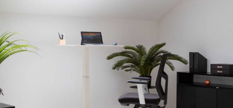 Bildausschnitt zeigt weißen mobilen Schreibtisch und schwarzen Bürostuhl