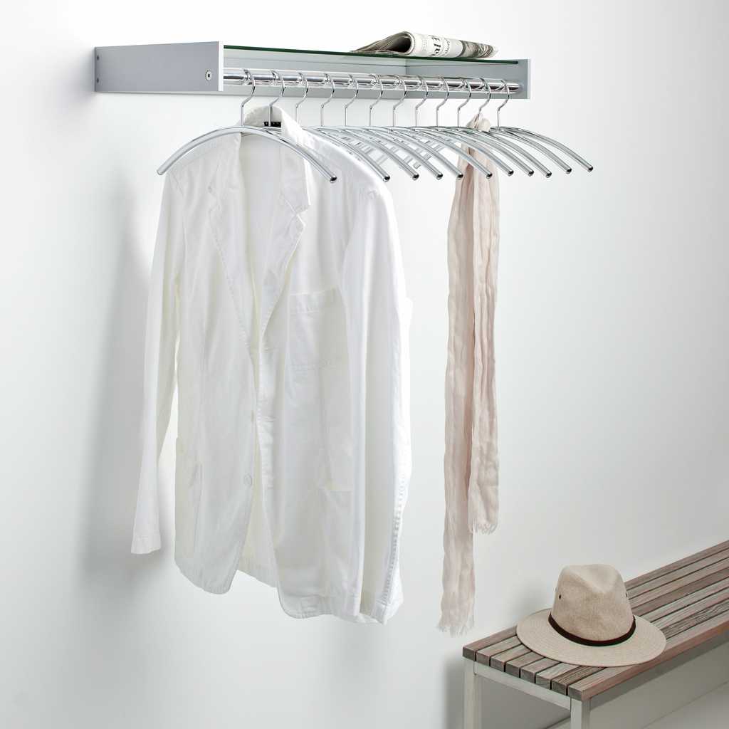 Wandgarderobe mit Ablage Garderobe für die Wand. Mit Ablage und Kleiderbügeln. An der Garderobe hängen Kleidungsstücke. Neben der Garderobe ist eine Bank.